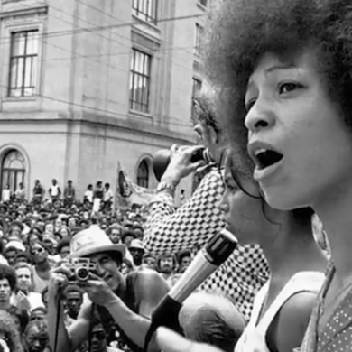 Angela Davis speaking to a large crowd during a civil rights rally, passionately addressing issues related to racial justice and systemic oppression.